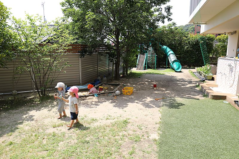 緑の多い園庭で遊ぶ子どもたち